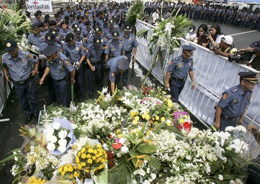 
 Philippine National Police officers light candles and offer prayers at the flower bedecked site where eight Hong Kong tourists were killed in a nearly 12-hour bus hostage standoff on Aug. 23, 2010, involving a dismissed police officer, at Manila's Rizal Park in the Philippines, Tuesday, Aug. 31, 2010. The 'Mass for Peace and Non-violence' was held as the Philippines worked to calm China's outrage over the bloodshed. (AP Photo/Bullit Marquez)
 