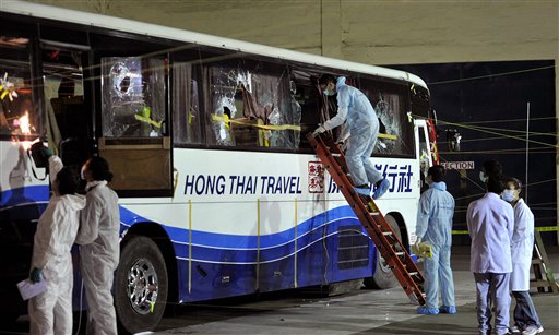
 Members of a Hong Kong police forensic team examine the tourist bus used in the hostage-hijacking on Aug. 23 by an ex-policeman at the auditorium at Camp Bagong Diwa in Taguig City, suburban Manila, Monday, Aug. 30, 2010. Hong Kong forensic experts on Monday inspected the bullet-peppered bus in which a hijacker killed eight tourists in Manila last week, as the Philippines worked to calm China's outrage over the bloodshed. (AP Photo/Noel Celis, Pool)
 