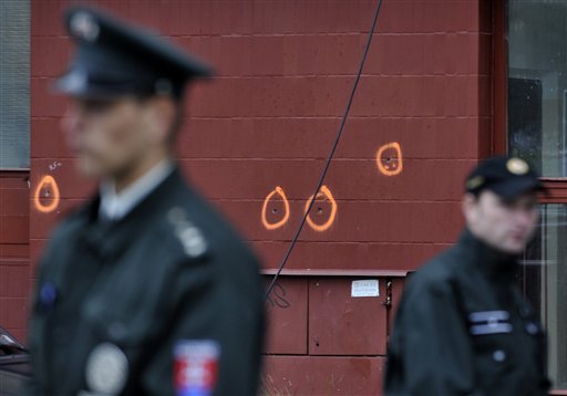 
 Slovakian police officers stand in front of the bullet marked wall of the building where an unknown man opened fire leaving eight people dead and dozens wounded in Devinska Nova Ves district of Bratislava, Slovakia, Monday, Aug. 30, 2010. (AP Photo/Bela Szandelszky)
 