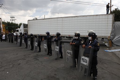 
 Mexico City police wearing face-masks guard a truck arriving with the bodies of some of the 72 migrants who were killed in northern Mexico while trying to reach the US border, at a funeral home in Mexico City, Wednesday Sept. 1, 2010. One of two survivors told Mexican investigators that the migrants were detained by people who identified themselves as Zetas, a drug gang that dominates parts of the northern state of Tamaulipas and then killed them when they refused to smuggle drugs. (AP Photo/Eduardo Verdugo)
 