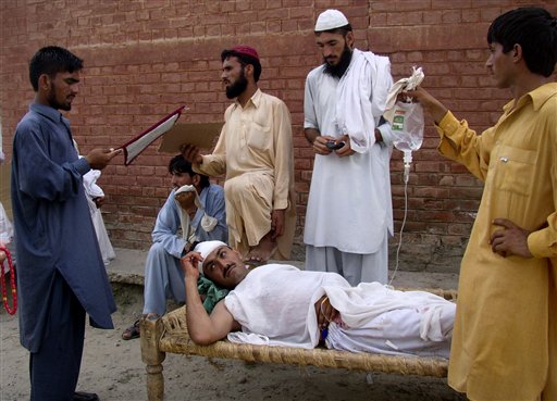 
 A man fans to his relative who was injured in suicide bombing at the compound of a local hospital in Lakki Marwat, Pakistan, Monday, Sept. 6, 2010. A suicide bomber detonated a car in an alley behind a police station in a strategically vital town in northwest Pakistan, killing scores of police and civilians in an explosion that shattered the station and neighboring homes, police said. (AP Photo/G.A. Marwat)
 