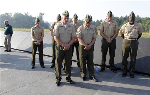 military personnel bow their heads as they observe a moment of ...