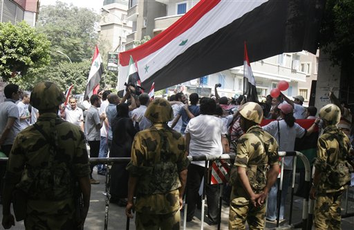 Protesters gather under a big Syrian flag while Egyptian army soldiers ...