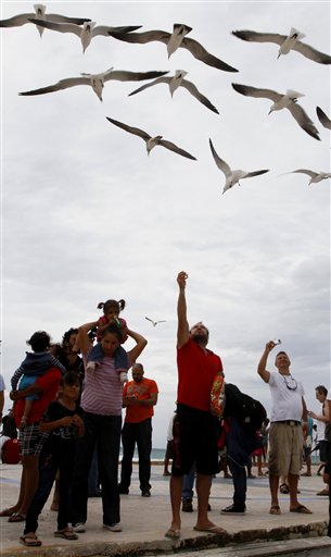 
 Tourists feed seagulls on the pier during the approach of Tropical Storm Rina in Playa del Carmen, Mexico, Thursday Oct. 27, 2011. Rina was downgraded from a hurricane to a tropical storm Thursday afternoon after many tourists had already cut short their trips to Cancun and other Caribbean resorts ahead of what once threatened to be a Category 3 storm. (AP Photo/Marco Ugarte)
 