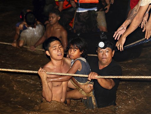 
 Residents are rescued by volunteers following a flash flood that inundated Cagayan de Oro city, Philippines, Saturday, Dec. 17, 2011. A tropical storm triggered flash floods in the southern Philippines, killing scores and missing more. Mayor Lawrence Cruz of nearby Iligan said the coast guard and other rescuers were scouring the waters off his coastal city for survivors or bodies that may have been swept to the sea by a swollen river. (AP Photo/Erwin Mascarinas)
 