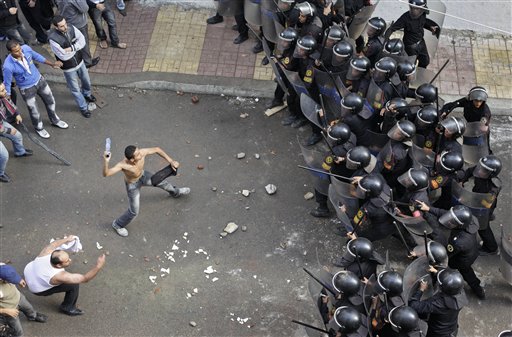 
 A Coptic protester, center-left, prepares to hurl an object at riot police during clashes between Coptic youths and riot police, who opened fire with rubber bullets and tear gas, in the streets outside the Saints Church and a neighboring hospital, in Alexandria, Egypt, Saturday, Jan. 1, 2011. A powerful bomb, possibly from a suicide attacker, exploded in front of a Coptic Christian church as a crowd of worshippers emerged from a New Years Mass early Saturday, killing at least 21 people and wounding nearly 80 in an attack that raised suspicions of an al-Qaida role. (AP Photo/Ben Curtis)
 