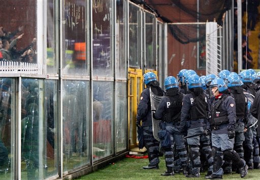 
 Italian police confront Serbia fans partially seen behind a partition at left prior to the start of a Group C, Euro 2012 qualifying soccer match between Italy and Serbia, at the Luigi Ferraris stadium in Genoa, Italy, Tuesday, Oct. 12, 2010. The Italy-Serbia European Championship qualifier was stopped after seven minutes of play on Tuesday after Serbia fans threw flares onto the pitch. (AP Photo/Antonio Calanni)
 