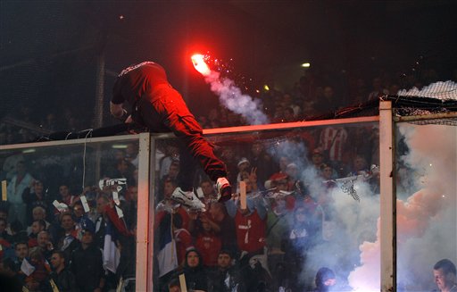 
 A Serbia fan cuts a net as he climbs onto a partition as a flare is thrown prior to the start of a Group C, Euro 2012 qualifying soccer match between Italy and Serbia, at the Luigi Ferraris stadium in Genoa, Italy, Tuesday, Oct. 12, 2010. The Italy-Serbia European Championship qualifier was called off after seven minutes of play on Tuesday after Serbia fans threw flares and fireworks onto the pitch. (AP Photo/Antonio Calanni)
 