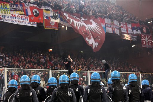 
 Italian police face Serbia fans prior to the start of a Group C, Euro 2012 qualifying soccer match between Italy and Serbia, at the Luigi Ferraris stadium in Genoa, Italy, Tuesday, Oct. 12, 2010. The start of the Italy-Serbia European Championship qualifier has been delayed due to Serbia fans throwing flares onto the pitch and lighting fireworks. (AP Photo/Carlo Baroncini)
 