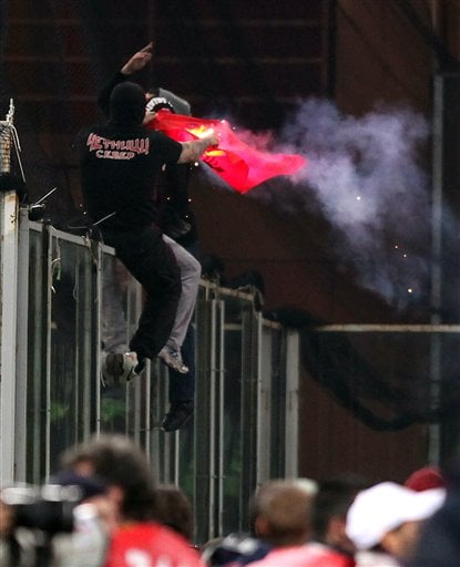 
 Serbia fan climbs onto a partition and burn what appears to be an Albanian flag prior to the start of a Group C, Euro 2012 qualifying soccer match between Italy and Serbia, at the Luigi Ferraris stadium in Genoa, Italy, Tuesday, Oct. 12, 2010. The Italy-Serbia European Championship qualifier has been stopped after seven minutes of play due to Serbia fans throwing flares onto the pitch and lighting fireworks. (AP Photo/Carlo Baroncini)
 