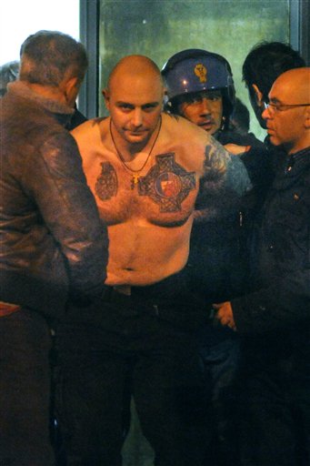 
 Serbian alleged ringleader identified by police as Ivan Bogdanov is detained outside the Luigi Ferraris stadium after a Group C, Euro 2012 qualifying soccer match between Italy and Serbia was called off, in Genoa, Italy, early Wednesday, Oct. 13, 2010. Police have detained 17 people including the alleged ringleader of rioting at an Italy-Serbia game that was abandoned when Serbia fans threw flares and fireworks onto the pitch, burned a flag and broke barriers. Police found the alleged instigator of the rioting in the trunk of a bus that was due to take the Serbian fans home from the European Championships qualifier. While his face was covered by a mask during the violence, police identified him by his tattooed arms and found explosive material with him. (AP Photo/Str)
 
