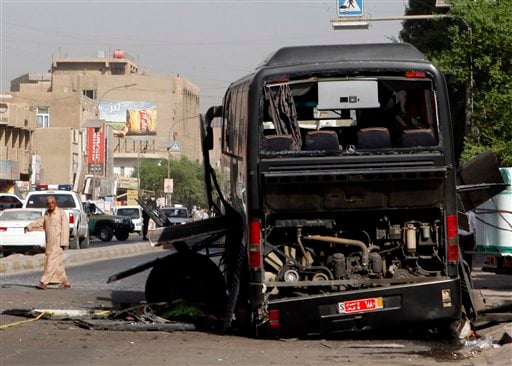 
 A man passes by a destroyed bus in Baghdad, Iraq, Tuesday, Oct. 19. 2010. Two bombs attached to buses carrying Iranian pilgrims detonated while they drove through downtown, police said. (AP Photo/Hadi Mizban)
 