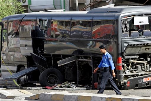 
 An Iraqi policeman passes by a destroyed bus in Baghdad, Iraq, Tuesday, Oct. 19. 2010. Two bombs attached to buses carrying Iranian pilgrims detonated while they drove through downtown, police said. (AP Photo/Hadi Mizban)
 