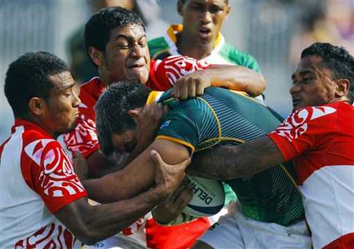 
 FILE - In this Oct. 11, 2010, file photo, Tonga players try to stop South Africa's Johannes Powell, center, during their rugby sevens match at the Commonwealth Games at Delhi University in New Delhi, India. Though injury rates in rugby are as high or higher than those in American football, there has never been a push to bring helmets and heavy padding into the game. (AP Photo/Victor R. Caivano, File)
 