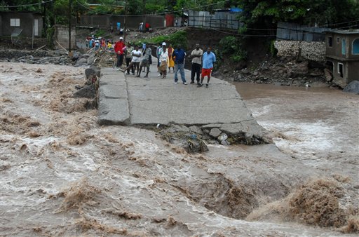 
 Residents watch floodwater as they stand on the destroyed the bridge that linked the towns of Kintyre and Kingston in Jamaica, Wednesday Sept. 29, 2010. Tropical Storm Nicole caused flooding and mudslides across Jamaica on Wednesday, leaving two confirmed dead and at least 12 more missing. (AP Photo/Collin Reid)
 