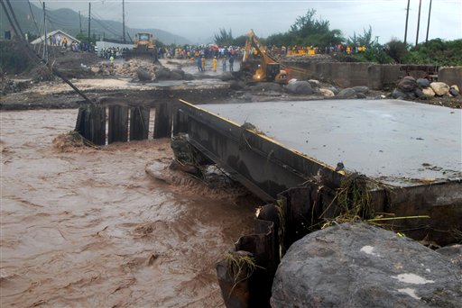 
 Residents of Harbour View look toward a collapsed bridge that links the parishes of St. Thomas and Portland to Kingston, Jamaica, Wednesday Sept. 29, 2010. Tropical Storm Nicole caused flooding and mudslides across Jamaica on Wednesday, leaving two confirmed dead and at least 12 more missing. (AP Photo/Collin Reid)
 