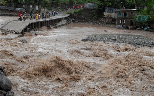 
 Residents watch floodwater as they stand on a destroyed the bridge that linked the towns of Kintyre and Kingston in Jamaica, Wednesday Sept. 29, 2010. Tropical Storm Nicole caused flooding and mudslides across Jamaica on Wednesday, leaving two confirmed dead and at least 12 more missing. (AP Photo/Collin Reid)
 
