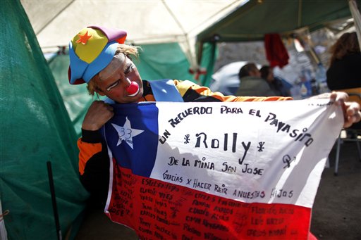 
 Clown Rolly shows a flag which was sent by the 33 trapped miners as a gift at the camp where relatives wait for news outside the San Jose mine in Copiapo, Chile, Wednesday Oct. 6, 2010. The words on the flag read in Spanish ' A souvenir for clown Rolly, from the San Jose mine, thanks for making our children laugh.' Thirty-three miners have been trapped deep underground in the copper and gold mine since it collapsed on Aug. 5. (AP Photo/Natacha Pisarenko)
 