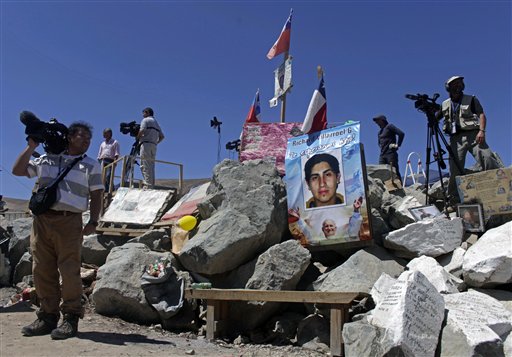
 Journalists stand at the entrance to the San Jose mine where a photograph of trapped miner Richard Villarroel stands near Copiapo, Chile, Wednesday Oct. 6, 2010. Thirty-three miners have been trapped deep underground in the copper and gold mine since it collapsed last Aug. 5. (AP Photo/Dario Lopez-Mills)
 