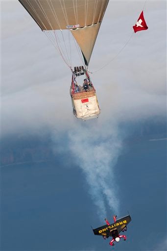 
 Swiss pilot Yves Rossy, the first man in the world to fly under a jet-fitted wing, speeds through the air to perform a looping near a hot air balloon in Bercher, western Switzerland, Friday, Nov. 5, 2010. (AP Photo/Keystone, pool, Laurent Gillieron)
 
