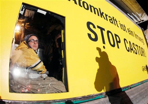 
 A member of environmental organization Greenpeace looks out of a window on which he is fixed in a van in Dannenberg, northern Germany, Monday, Nov. 8, 2010. The van with its special box construction blocks the first cross road where a transport of nuclear way is supposed to pass soon. The inside box was put down on the street so that the van cannot be moved. The castor train with nuclear waste was underway from French La Hague with delay due to various protests of anti nuclear activists. (AP Photo/Michael Probst)
 