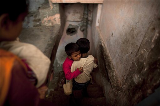 
 A boy carries another and walks down a stairs as residents of an adjacent building are evacuated by police after a four-story apartment building collapsed in New Delhi, India, Tuesday, Nov. 16, 2010. Dozens of residents were killed and scores injured when the 15-year-old building housing about 200 people collapsed late Monday night, police reports said. (AP Photo/Kevin Frayer)
 