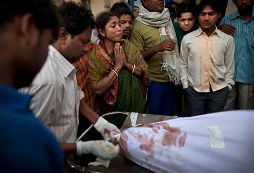 
 An Indian woman, center, reacts as the body of her husband who died in the collapse of a four-story apartment building is taken away for burial from a mortuary in New Delhi, India, Tuesday, Nov. 16, 2010. Dozens of residents were killed and scores injured when the 15-year-old building housing about 200 people collapsed late Monday night, police reports said. (AP Photo/Kevin Frayer)
 