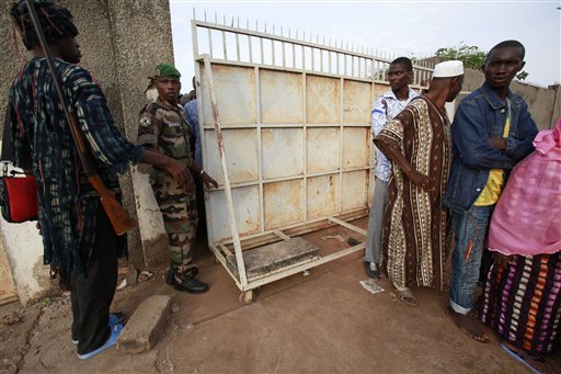 
 A traditional hunter, left, and a former member of the rebel New Forces army, second left, now part of the national army, control access to a polling station as part of a mixed election security force, in the former rebel stronghold of Bouake, in northern Ivory Coast, Sunday, Oct. 31, 2010. The West African nation of Ivory Coast held a long-awaited presidential election Sunday, the first since civil war erupted in 2002 and split the world's leading cocoa producer in half. (AP Photo/Rebecca Blackwell)
 