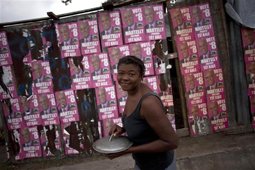 
 A woman walks next to campaign signs of Haiti's presidential candidate Michel Martelly in Port-au-Prince, Haiti, Tuesday, Dec. 7, 2010. (AP Photo/Guillermo Arias)
 