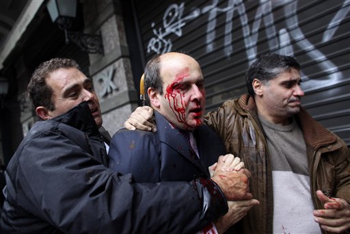 
 A bodyguard, left, leads off former Greek development minister Costis Hatzidakis, center, after he was attacked by protesters in Athens, Wednesday Dec. 15, 2010. Protesters clashed with riot police across Athens on Wednesday, torching cars, hurling gasoline bombs and sending Christmas shoppers fleeing in panic during a general strike against the government's latest austerity measures. (AP Photo)
 