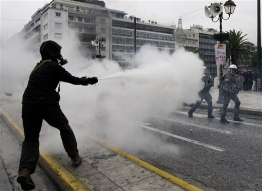 
 A protester uses a fire extinguisher against riot police during clashes in Athens, Wednesday, Dec. 15, 2010. Hundreds of protesters clashed with riot police across central Athens, smashing cars and hurling gasoline bombs during a massive labor protest against the government's austerity measures. The violence occurred after some 20,000 protesters marched to parliament during a general strike against a new round of labor reforms in the crisis-hit country. (AP Photo/Alkis Konstantinidis)
 