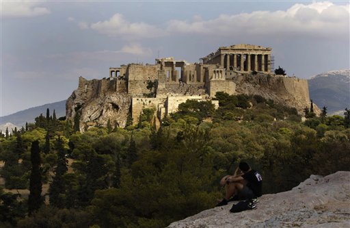 
 In this photo taken Sunday, Sept. 5, 2010, visitors sit on a rocky outcrop looking out onto the Acropolis, with the newly-restored temple of Athena Nike, distinguished by its four Ionic columns, on a platform below and to the left of the Parthenon, in Athens, Sunday, Sept. 5, 2010. A ten-year restoration project has just been completed on the 2,400-year-old temple, which was dismantled to ground level and rebuilt to correct damage from ground subsidence and rusting internal joints. (AP Photo/Petros Giannakouris)
 