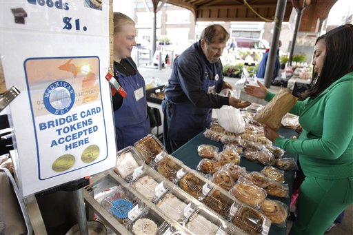
 Temeka Williams, right, of Detroit, uses her bridge card tokens for a purchase from Elizabeth and Gary Lauber from Sweet Delights at the Farmer's Market in Detroit, Saturday, Sept. 11, 2010. (AP Photo/Carlos Osorio)
 