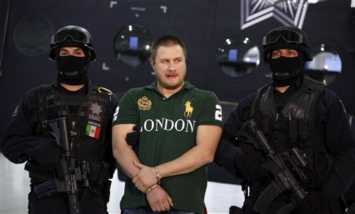 
 Federal police stand guard by Texas-born kingpin Edgar Valdez Villarreal, alias 'the Barbie,' center, during his presentation to the press in Mexico City, Tuesday Aug. 31, 2010. Valdez, who was captured on Monday by federal police, faces drug trafficking charges in the U.S. and has been blamed for a vicious turf war that has included bodies hung from bridges and shootouts in central Mexico. (AP Photo/Alexandre Meneghini)
 