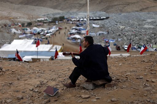 
 Evangelical priest Javier Soto plays a guitar at the camp where the relatives of 33 trapped miners wait outside the collapsed San Jose mine in Copiapo, Chile, Tuesday Aug. 31, 2010. Thirty-three men stuck far underground are now the longest-trapped miners in recent history as a huge drill begins digging a planned escape route. The miners have been trapped since Aug. 5. (AP Photo/Roberto Candia)
 