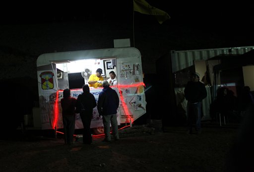 
 People ask for food, handed out by Chilean authorities, at the camp where relatives of 33 trapped miners wait for news outside the San Jose mine in Copiapo, Chile, Monday, Aug. 30, 2010. The miners, who have been trapped since the shaft they were working in collapsed on Aug. 5, were confirmed to be alive Aug. 22 when they were reached by rescue teams via a small hole through which they could pass messages and see the miners with a camera. (AP Photo/Roberto Candia)
 