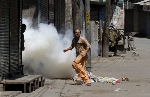 
 A Kashmiri protester runs as a tear gas shell exploded near him after police fire at a group of people playing carom board on a street during a curfew hours, in Srinagar, India, Monday, Aug. 30, 2010. (AP Photo/Mukhtar Khan)
 