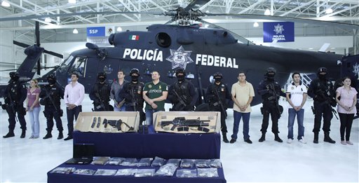 
 Federal police stand guard by Texas-born Edgar Valdez Villarreal, alias 'the Barbie,' eighth from left, and his alleged collaborators during their presentation to the press in Mexico City, Tuesday Aug. 31, 2010. Valdez, who was captured on Monday by federal police, faces drug trafficking charges in the U.S. and has been blamed for a vicious turf war that has included bodies hung from bridges and shootouts in central Mexico. (AP Photo/Alexandre Meneghini)
 