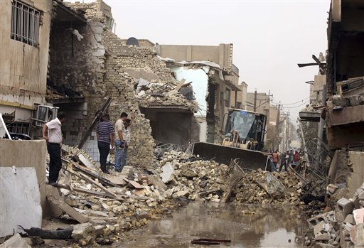 
 Iraqis gather as a bulldozer removes debris after a car bomb attack in Baghdad's Kazimiyah neighborhood, Iraq, Sunday, Sept. 19, 2010. Two car bombs exploded during the morning rush hour killing and wounding scores of people, police said. (AP Photo/Karim Kadim)
 