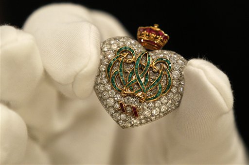 
 A Sotheby's employee pose with a 1957 emerald, ruby and diamond brooch on display at the auction house in London, Thursday, Sept. 23, 2010. The brooch, formerly in the collection of the Duchess of Windsor, is made by Cartier to commemorate the Duke and Duchess twentieth wedding anniversary is to be auctioned in 'The Jewels of the Duchess of Windsor' sale on Nov. 30 with an estimated price of 100,000 to 150,000 pounds (US$156,641 to 234,962 or 117,559 to 176,339 euro). (AP Photo/Sang Tan)
 