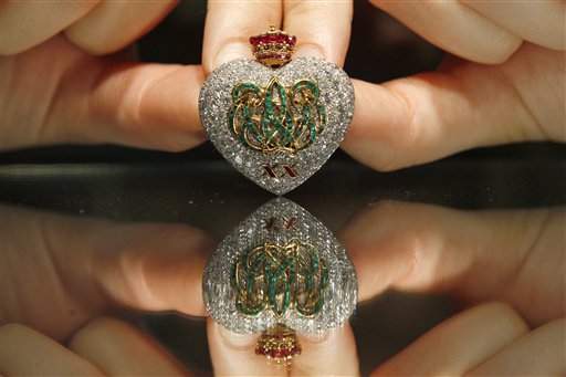 
 A Sotheby's employee pose with a 1957 emerald, ruby and diamond brooch on display at the auction house in London, Thursday, Sept. 23, 2010. The brooch, formerly in the collection of the Duchess of Windsor, is made by Cartier to commemorate the Duke and Duchess twentieth wedding anniversary is to be auctioned in 'The Jewels of the Duchess of Windsor' sale on Nov. 30 with an estimated price of 100,000 to 150,000 pounds (US$156,641 to 234,962 or 117,559 to 176,339 euro). (AP Photo/Sang Tan)
 