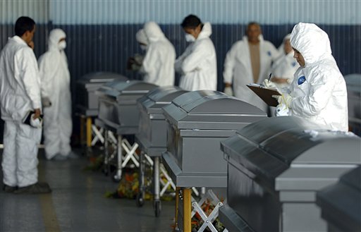 
 Forensic experts inspect the coffins containing the remains of 16 Hondurans who were killed in Mexico while trying to reach the U.S. border, before returning the bodies to family members in Tegucigalpa, Honduras, Wednesday Sept. 1, 2010. The bodies of 72 Central and South American migrants, who were allegedly killed by a Mexican drug cartel, were found within 100 miles of the U.S. border on Aug. 24. (AP Photo/Fernando Antonio)
 