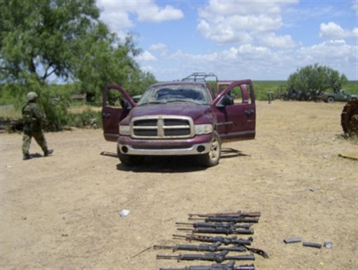 
 In this photo released by Mexico's Secretary of Defense (SEDENA), a soldier walks past a pick-up truck and seized weapons near the town of Ciudad Mier in northern Mexico, Thursday Sept. 2, 2010. According to the Secretary of Defense, gunmen opened fire on soldiers after an airborne patrol detected armed men guarding a home near this town. At least 25 gunmen were killed, two soldiers were injured and three people held captive were freed. (AP Photo/SEDENA)
 