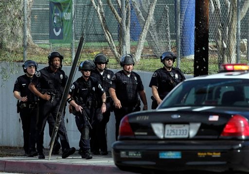 
 A group of police officers search outside El Camino Real High School in the Woodland Hills section of Los Angeles, Wednesday, Jan. 19, 2011. A school police officer was shot near the high school but his bulletproof vest took the hit Wednesday, one day after an accidental shooting wounded two students at a school on the other side of the city, authorities said. (AP Photo/Jae C. Hong)
 
