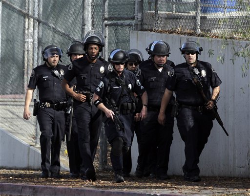 
 A group of police officers search outside El Camino Real High School in the Woodland Hills section of Los Angeles, Wednesday, Jan. 19, 2011. A school police officer was shot near the high school but his bulletproof vest took the hit Wednesday, one day after an accidental shooting wounded two students at a school on the other side of the city, authorities said. (AP Photo/Jae C. Hong)
 