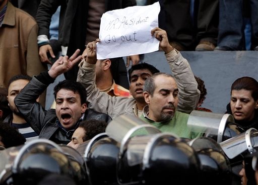 
 A man holds up a placard reading 'Mr. President go out' as angry Egyptian activist shouts at anti-riot policemen in front of the journalists syndicate in downtown Cairo, Egypt, Wednesday, Jan. 26, 2011. A small gathering of Egyptian anti-government activists tried to stage a second day of protests in Cairo Wednesday in defiance of a ban on any gatherings, but police quickly moved in and used force to disperse the group. (AP Photo/Ben Curtis)
 