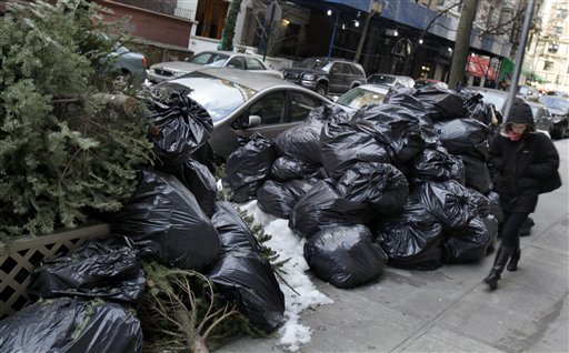 
 A woman walks by bags of uncollected trash and discarded Christmas trees on New York's Upper West Side, Thursday, Jan. 6, 2011. Another storm took aim at New York City, where Mayor Michael Bloomberg was still under fire for slow cleanup of a stubborn winter blast that kept streets clogged for days and delayed trash pickups, causing uncollected garbage to pile up for more than a week. (AP Photo/Richard Drew)
 