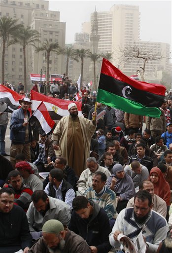 
 An Egyptian raise Libya's old national flag, in dupport to Libyans at Tahrir Square, the focal point of the Egyptian uprising, in Cairo, Egypt, Friday, Feb.25, 2011.The deputy to Osama bin Laden issued al-Qaida's second message since the Egyptian uprising, accusing the nation's Christian leadership of inciting interfaith tensions and denying that the terror network was behind last month's bombing of a Coptic church in Alexandria that killed 21 and sparked protests. (AP Photo/Amr Nabil)
 