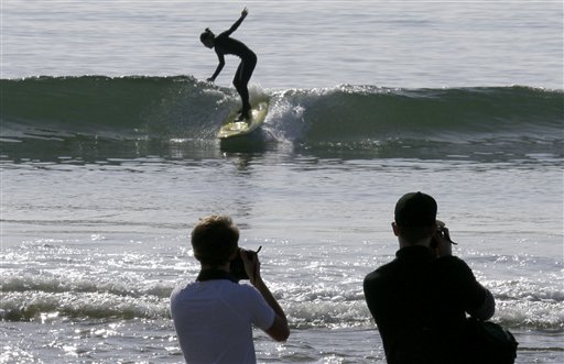 
 Visitors take photos as a surfer takes a wave at about the time the effects of a tsunami were expected, at Surfrider Beach in Malibu, Calif., Friday, March 11, 2011. Though waves surged in other areas along California's coast from a tsunami triggered by the massive earthquake in Japan, there was little noticeable change in conditions at Malibu, where the beach was not closed to the public. (AP Photo/Reed Saxon).
 